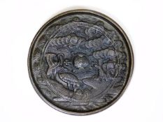 A Chinese bronze mirror with relief decor to verso