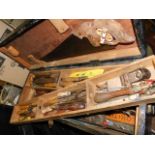 A large wooden toolbox with contents including two