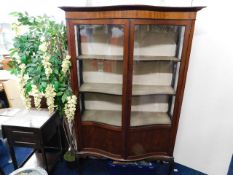An Edwardian serpentine front display cabinet on c