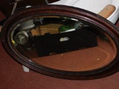 An oval stained wood framed mirror