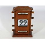 An early 20thC. oak cased desk calendar