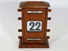 An early 20thC. oak cased desk calendar