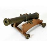 A brass desk cannon on wooden plinth with brass wh