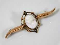 An antique 9ct gold brooch set with carved white c