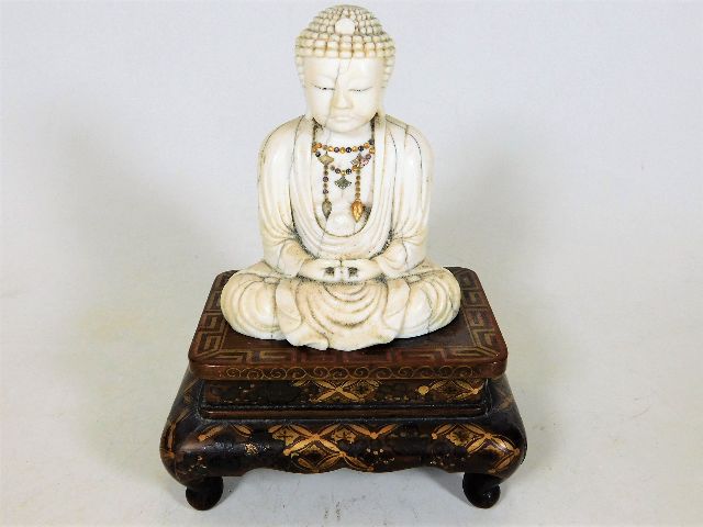 A 19thC. Tibetan ivory Buddha sat on rosewood plin