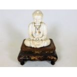 A 19thC. Tibetan ivory Buddha sat on rosewood plin