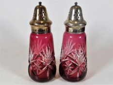A pair of cut glass cranberry overlay sifters with