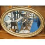 A large gilt framed bevelled edge oval wall mirror