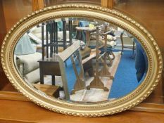 A large gilt framed bevelled edge oval wall mirror