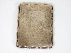 A silver card case with chased decor, damage to hi