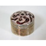 A white metal pill box with enamelled top