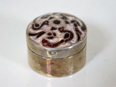 A white metal pill box with enamelled top