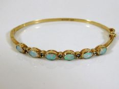 A 9ct gold bangle set with six opals 9.2g