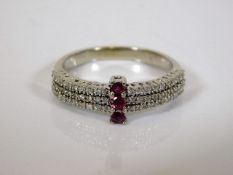 A white metal ring set with diamonds & three rubie