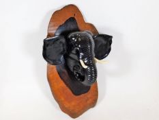 An antique carved elephant mounted on hardwood pla