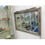 A modern carved silver coloured frame wall mirror