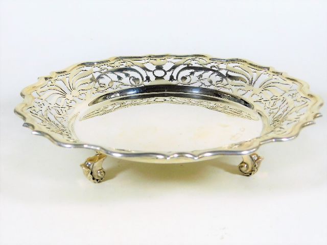 A footed silver dish with reticulated edge