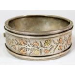 A decorative silver bangle with applied yellow & r