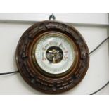 A small carved wall mounted barometer with enamell