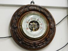 A small carved wall mounted barometer with enamell