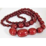 A large red amber beaded necklace 44in long approx
