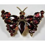 A yellow metal butterfly brooch set with garnets,