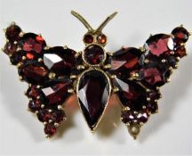 A yellow metal butterfly brooch set with garnets,