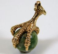 A well carved 9ct gold claw pendant clasping a jad
