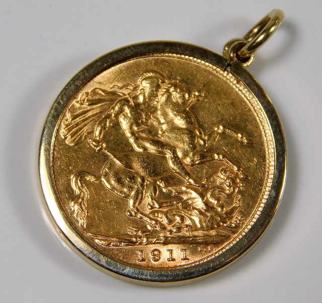 A George V 1911 full gold sovereign within 9ct gold holder approx. 9.3g