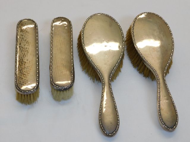 Four matching silver backed brushes