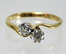 An 18ct gold crossover ring set with two diamonds,