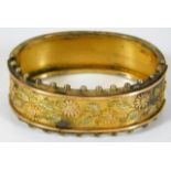 A yellow metal bangle with applied two tone leaf d