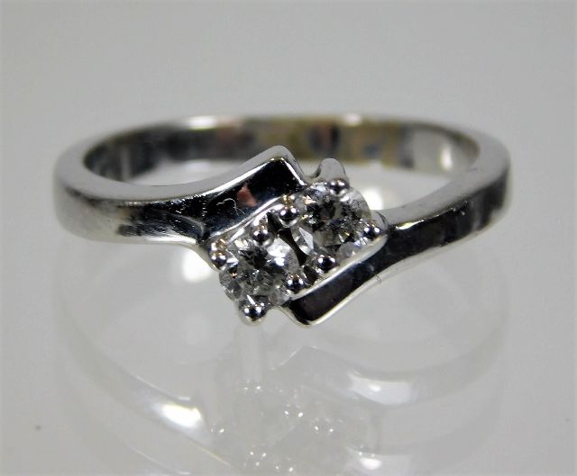 A white metal, tests as 18ct gold, two stone ring with crossover style setting of 0.2ct diamonds 3.7