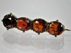 A yellow metal bar brooch with red stones