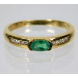 An 18ct gold ring set with emerald with four diamo