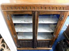 An oak glazed bookcase with linen fold doors