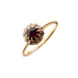 Dress ring set central ruby coloured stone with a diamond surround, the shank stamped 18ct, size M