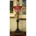 Victorian oil lamp having a clear glass reservoir, reeded brass and cast iron base with stylised