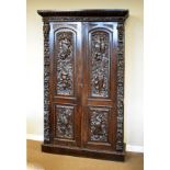 Late 19th/early 20th Century heavily carved oak two door cupboard fitted four shelves enclosed by