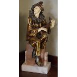 Art Deco style bronzed metal and faux ivory figure of a clown seated on a pedestal and playing a