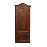 George III oak two section standing corner cupboard, the upper section fitted arch shaped fielded