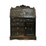 Early 20th Century heavily carved dark oak bureau, the fall flap opening to reveal a fitted