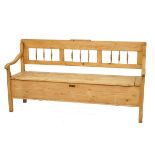 Stripped pine box seat settle having a spindle back and scroll arms and standing on square
