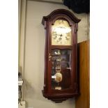 Reproduction mahogany finish cased wall clock, the brass dial with Roman numerals, pendulum window
