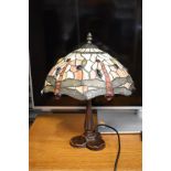 Modern bronzed table lamp with a stained and leaded glass style shade having dragonfly decoration
