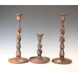 Pair of oak barley twist candlesticks together with a similar smaller candlestick Condition: