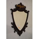 Mahogany framed shield shaped bevelled wall mirror having a giltwood bird pediment Condition:
