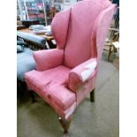 Georgian style wing back library chair upholstered in pink fabric and standing on cabriole