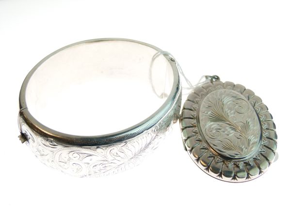 Snap bangle with engraved decoration and a silver oval locket with engraved foliate decoration