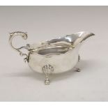 George VI silver sauce boat having an acanthus scroll handle, wavy rim and standing on triple pad